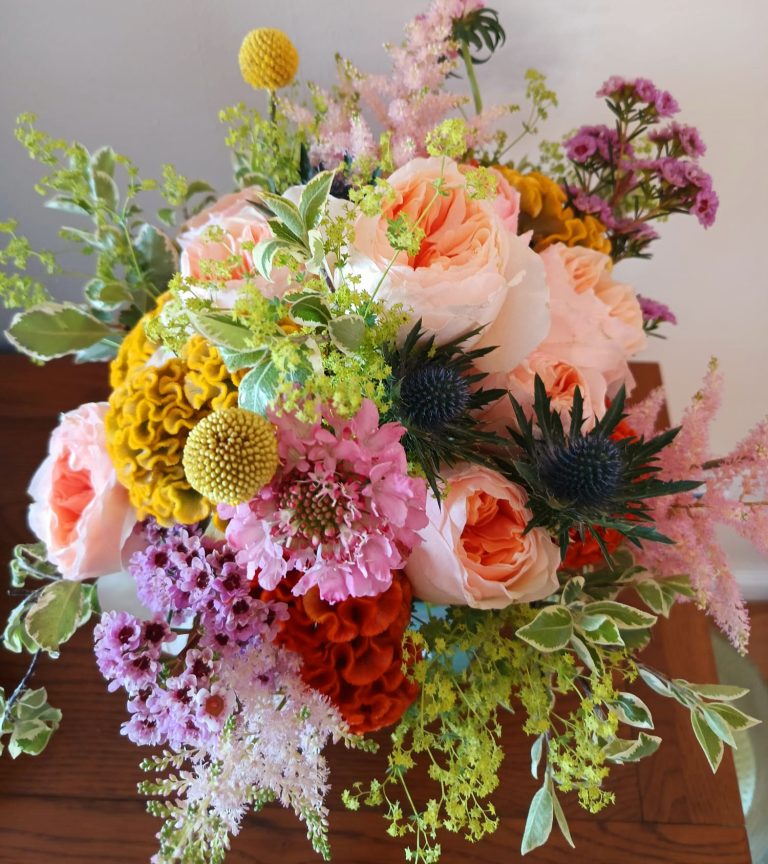 beautiful garden roses mixed with summer blooms in tones of peach and oranges